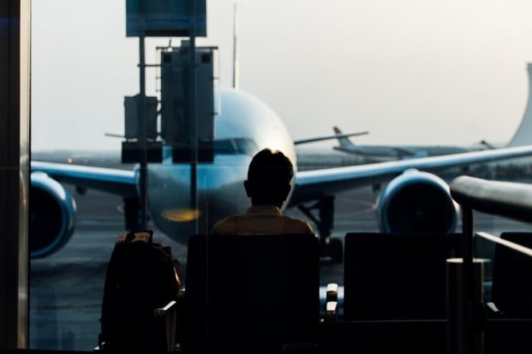 rear-view-man-sitting-airport-lobby-against-airplane_1048944-5351604